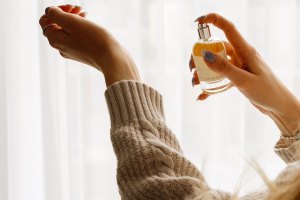 A woman's hand spritzes perfume onto her other wrist.