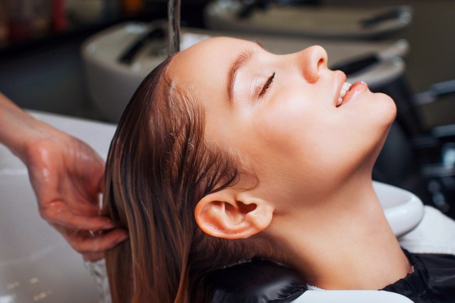 brunette woman at the sink getting hair washed