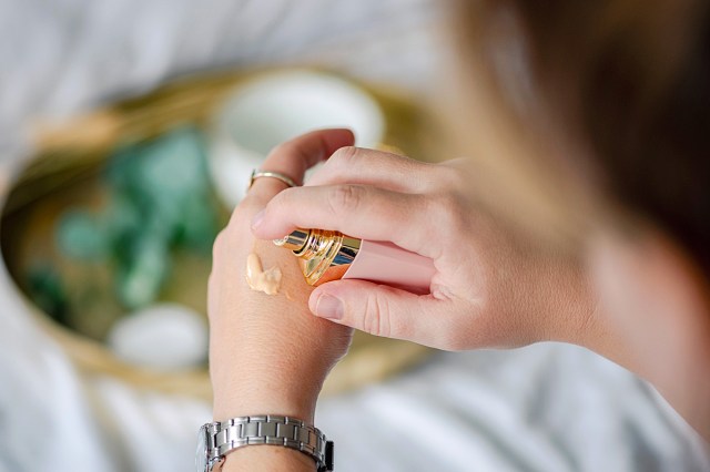 woman putting foundation on her hand 