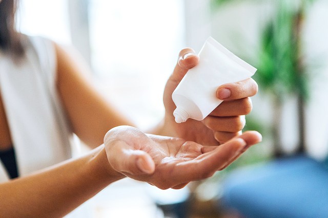 Young woman squeezing hand sanitiser on hand 