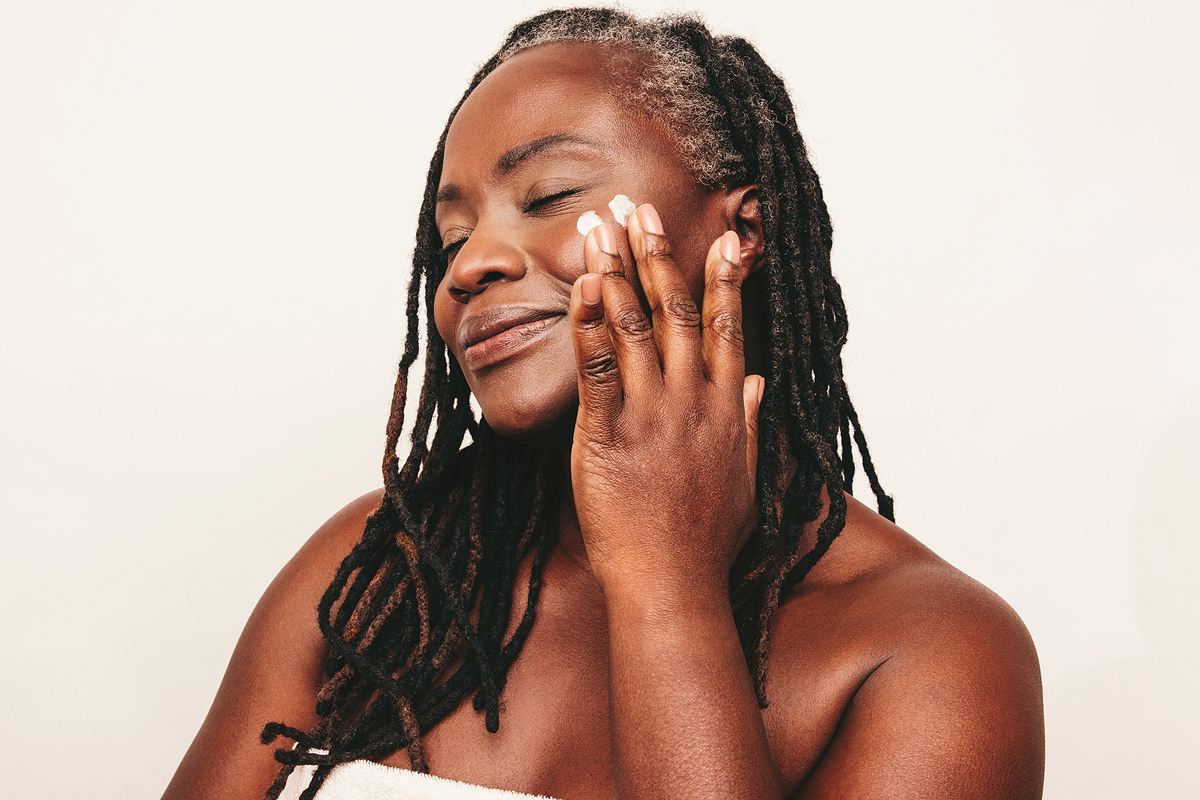 dark skin older woman applying skincare