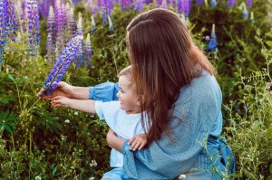 woman in blue dress holding a baby in a field