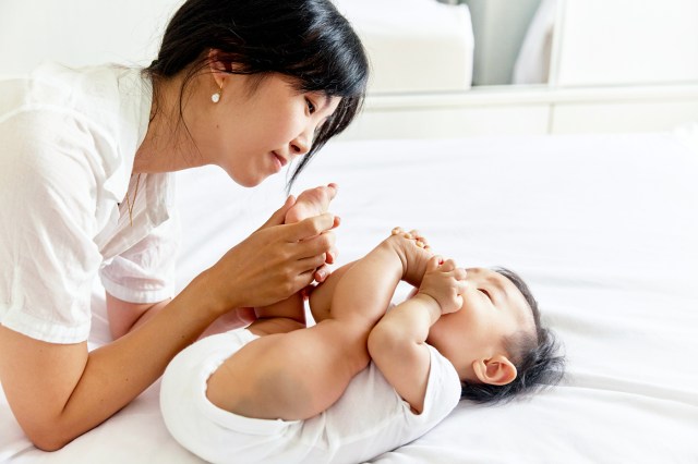 a woman holding a baby on top of a bed