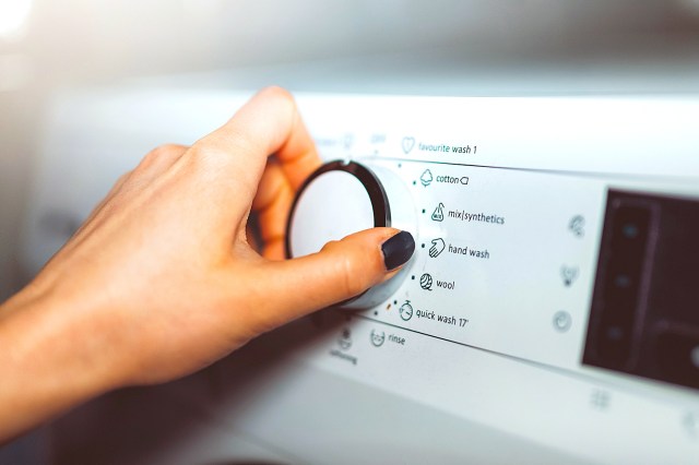 Woman choosing program on washing machine