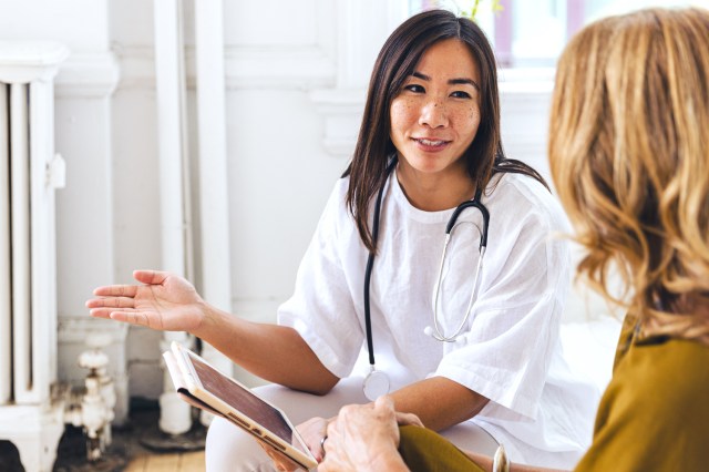 Smiling doctor discussing with female patient at clinic 