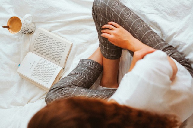 person in black and white plaid pants lying on bed