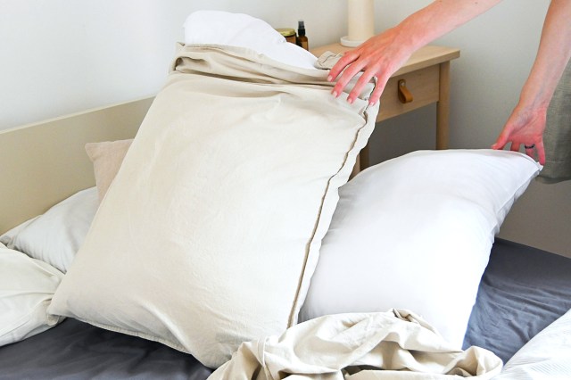 a person reaching for a pillow on a bed