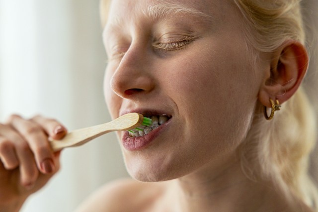 a woman brushing her teeth with a toothbrush