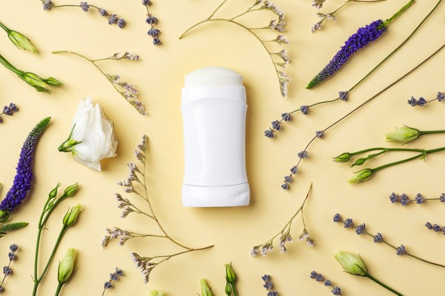 Flat lay composition with deodorant and herbs on color background