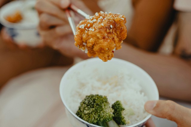 woman in white tank top holding spoon with rice