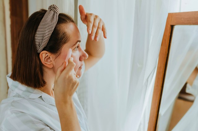 a woman doing a face massage in front of a mirror