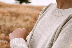 man in gray sweater standing on brown field during daytime