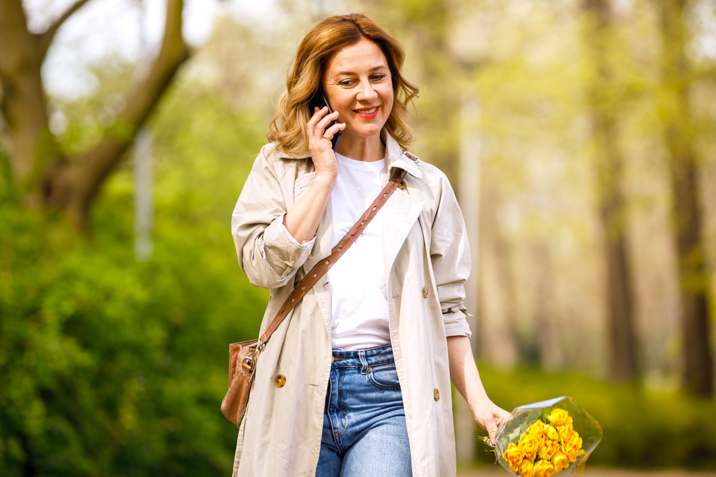 Joyful woman talking on the phone while taking a relaxing walk at the park