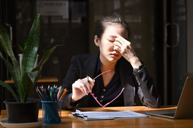 Tired businesswoman take off glasses and massaging nose bridge.