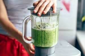 Close-up blender process. Cooking a green spring smoothie. Mixing in a blender bowl.