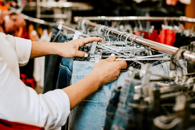 Woman shopping for clothes, touching jeans on a rack