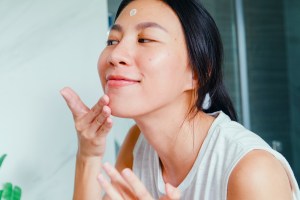 Woman putting cream on her face