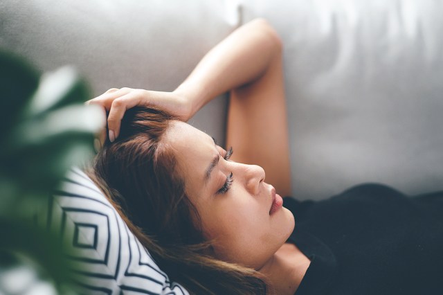 Depressed young asian woman lying on couch at home living room