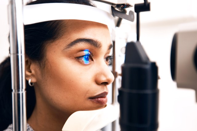 Woman getting eye exam, head in machine