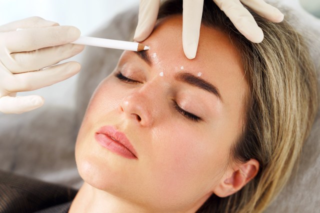 Doctor making marks on client's face before filler injection