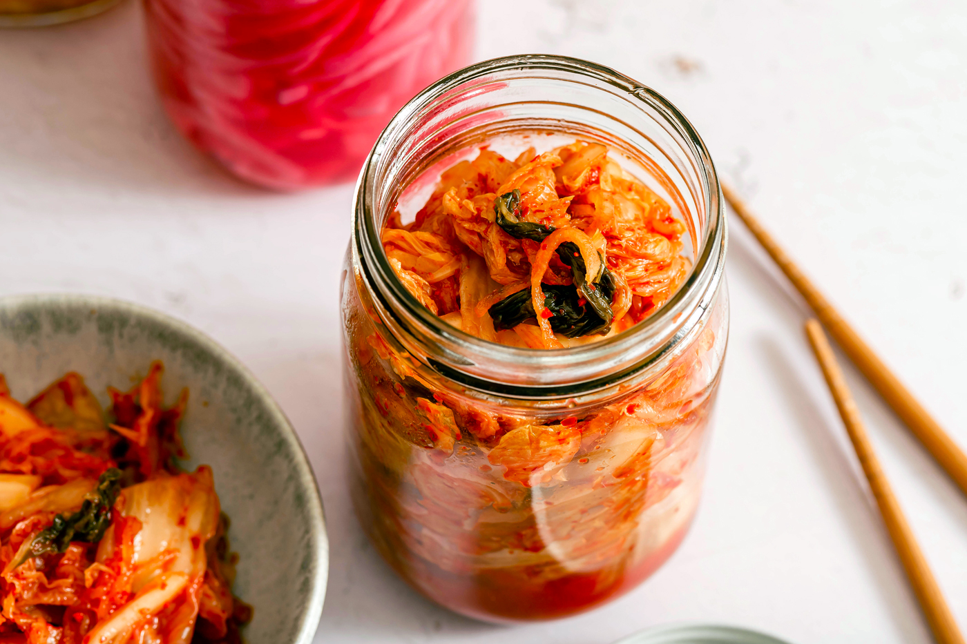 a glass jar filled with food next to a bowl of noodles