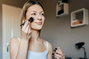 Woman using makeup brush on her cheek