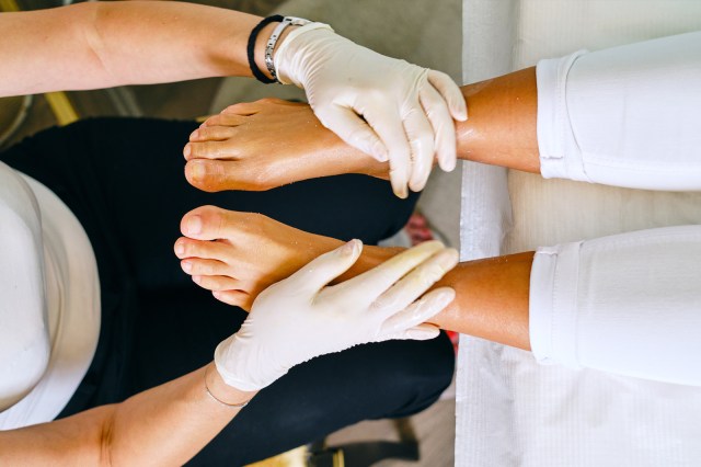 Massage therapist massaging young women's feet at a beauty spa