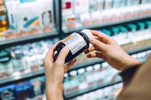 Close up of person holding vitamin bottle and reading the label in a store