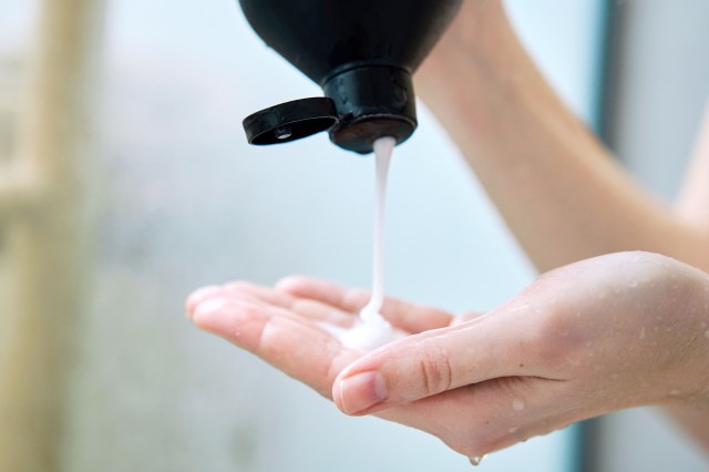 woman squirting shampoo out of the bottle