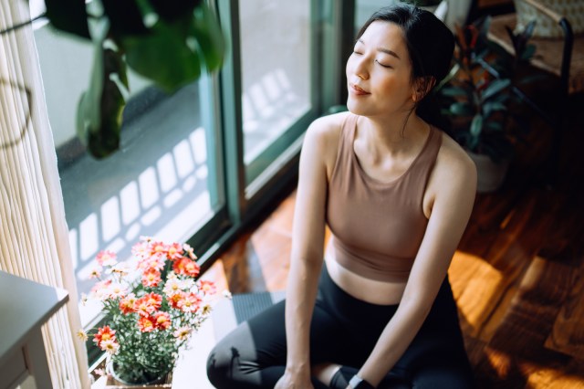 Woman sitting on exercise mat at home