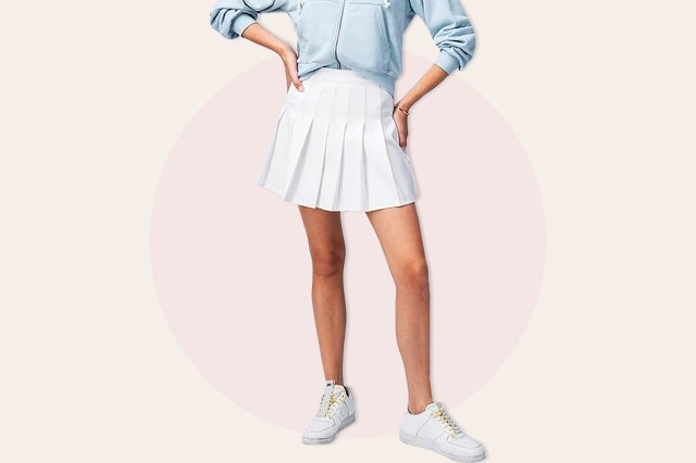 Cropped image of woman wearing white tennis skirt, blue sweater