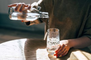 A woman at the table pours a glass of water from a bottle