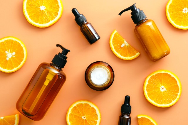 Still life of skin care product bottles and orange slices on orange background