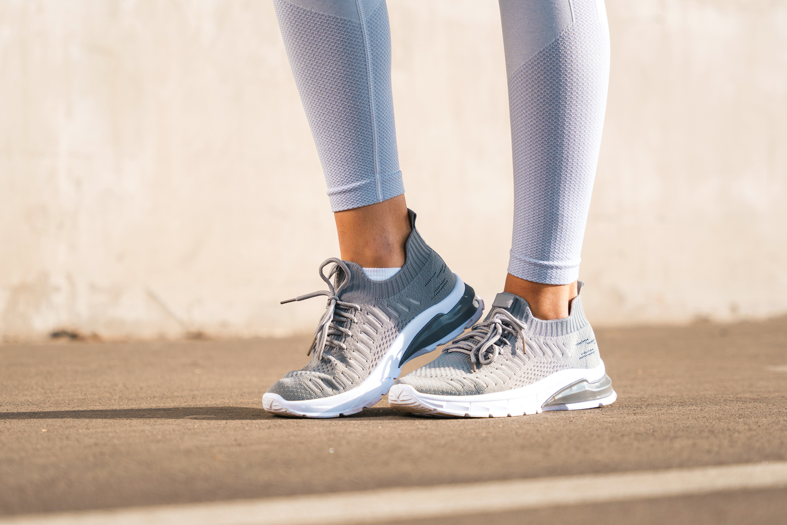 Legs of a sportswoman in modern gray running shoes and leggings