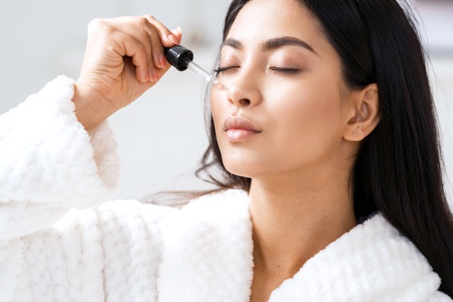 Woman applying serum to her face with dropper