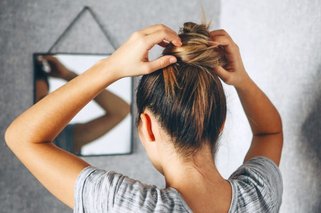 Back view of woman putting her hair up in a bun