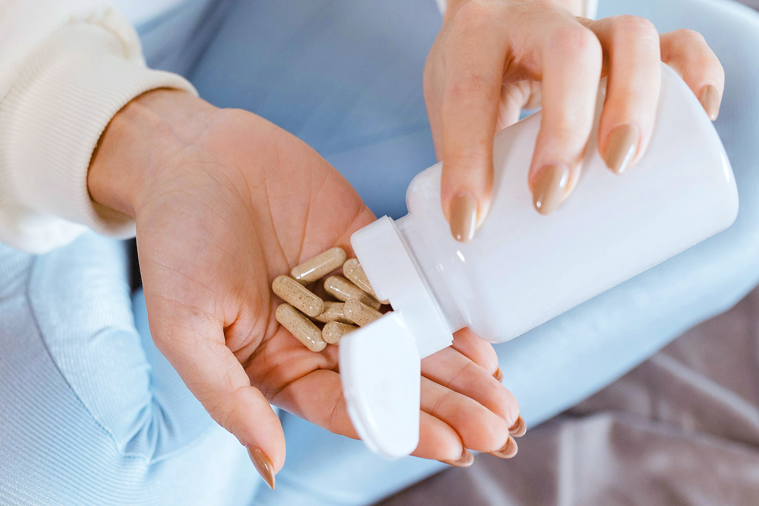 Close up of woman pouring pills in her hand from bottle