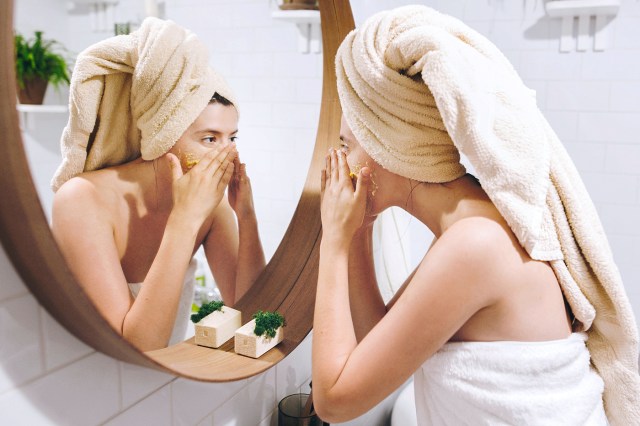 Woman looking in mirror washing her face