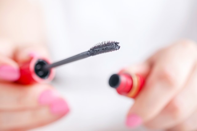 Close up of person holding open mascara tube