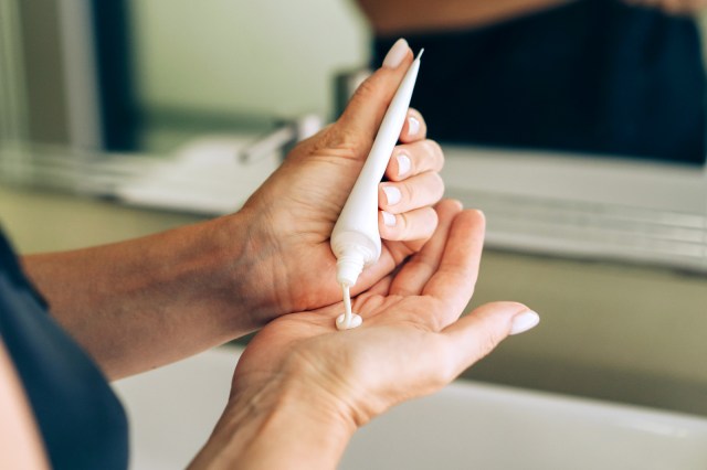 Close up of woman squeezing cream into her hands