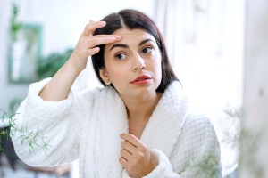 Woman looking at her face in mirror