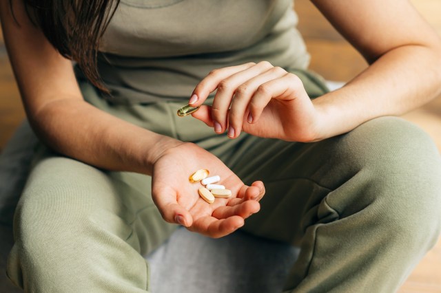 Unrecognizable woman holds vitamins and omega-3 in her palm for health and beauty