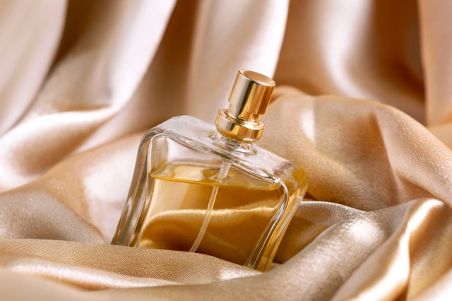 glass bottle of perfume on a background of golden silk