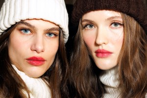 Close up of two models wearing winter hats, blush and red lipstick