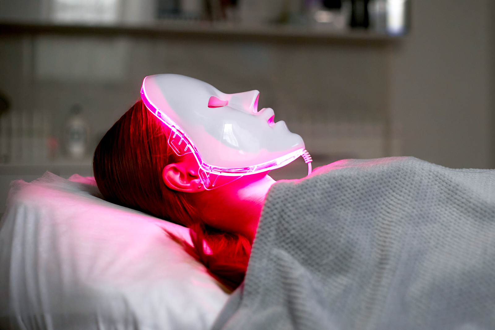 Woman using red light therapy mask