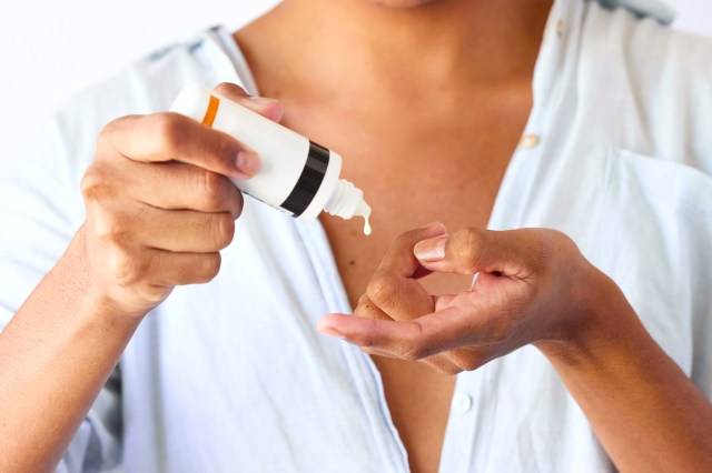 Close up of woman using sunscreen bottle