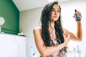 Woman spraying product in her curly hair