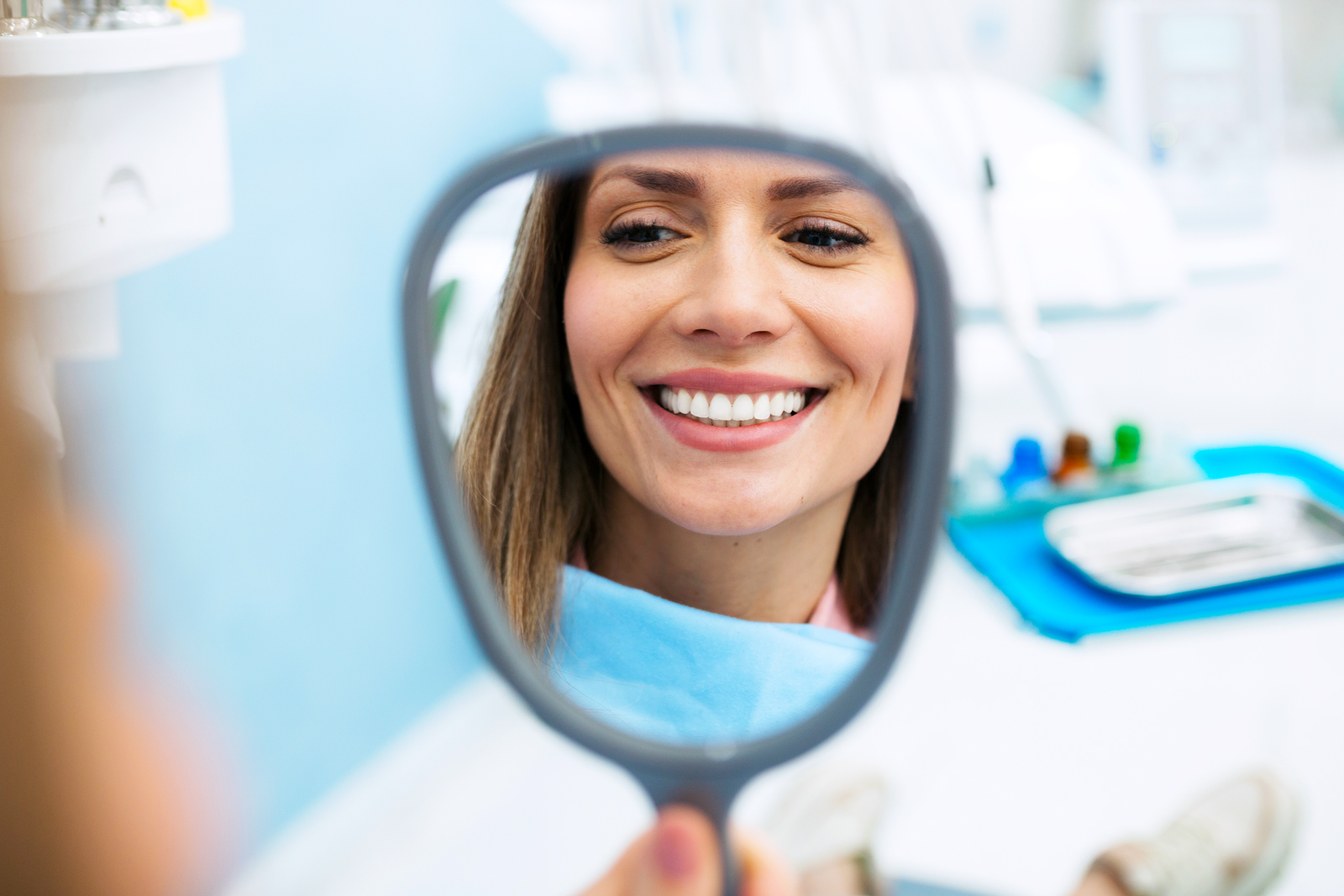 Woman in dentist office looking at herself in mirror