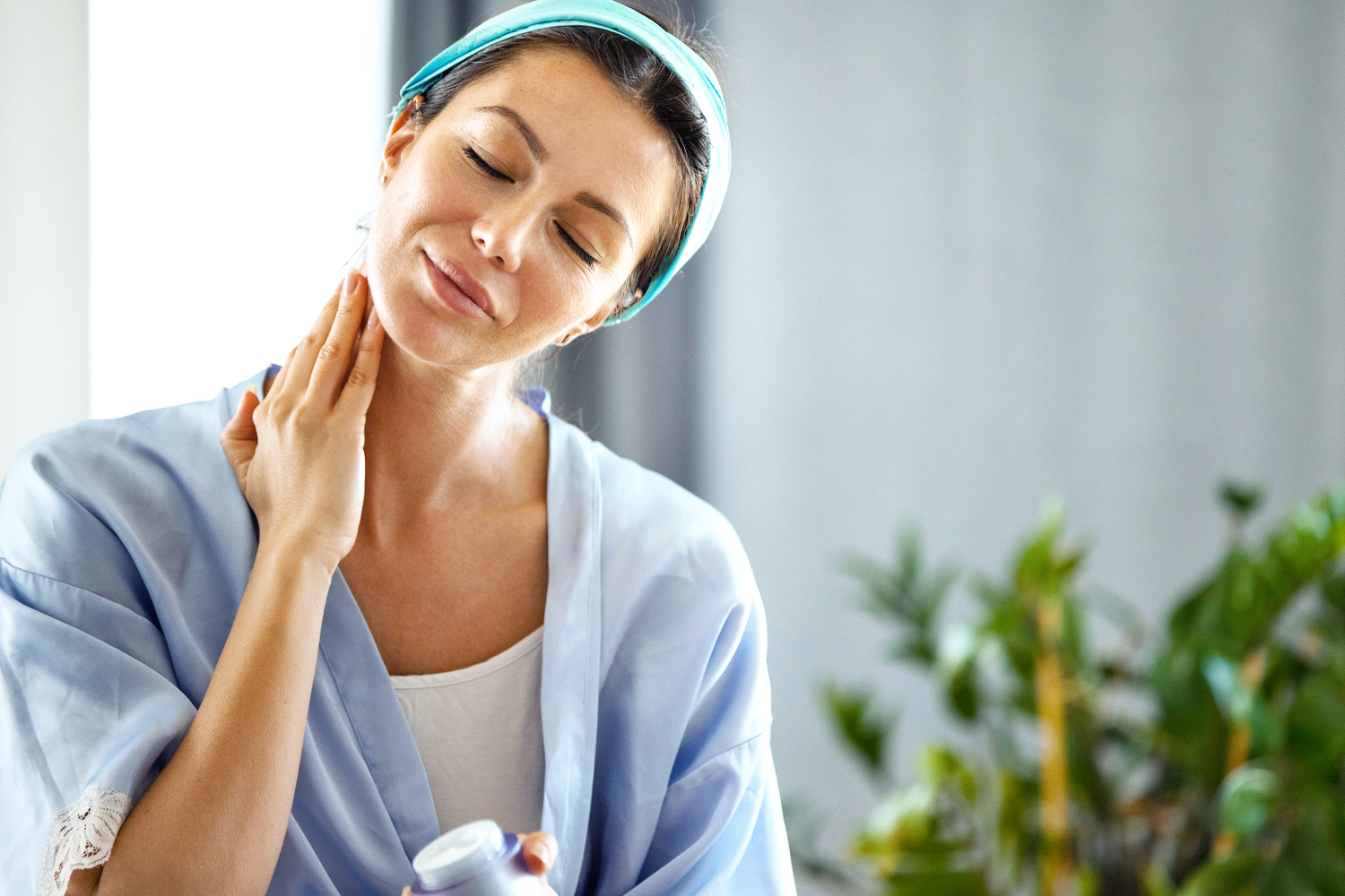 Woman applying cream to her neck