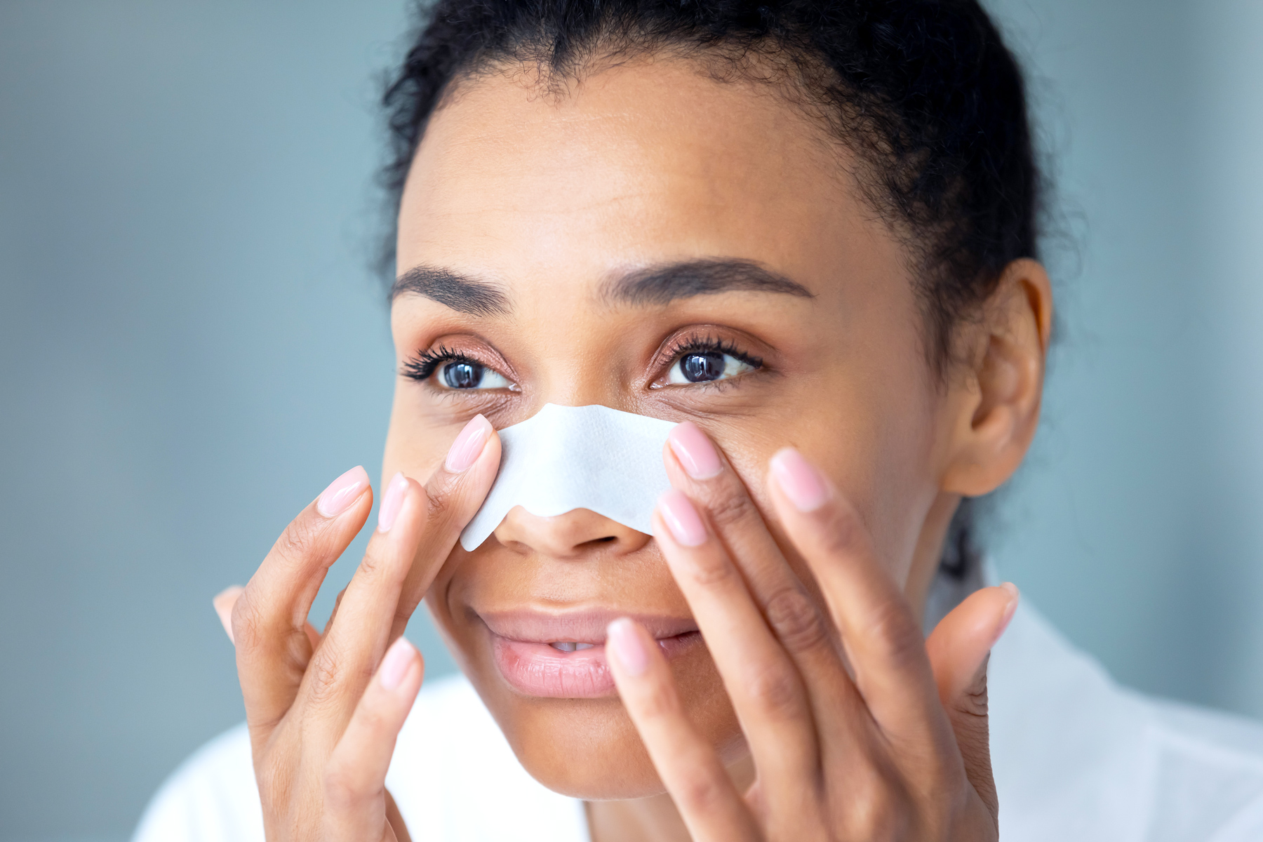 Woman using blackhead nose strip on her face